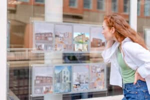 Prospective buyer studying estate agent window listings, the point to check flood risk before buying a property.