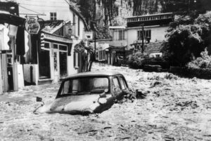 Car submerged in muddy floodwater on a village high street during the Great Flood of 1968 in the Bristol area.