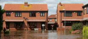 Flooded red-brick homes on a UK residential street, showing why flood risk and the UK housing market are linked.
