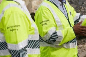 Environment Agency officers in branded hi-vis jackets on a development site, reflecting the Environment Agency flood risk planning consultee role.