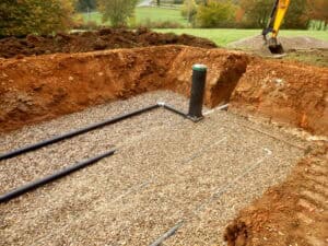 Drainage field under construction, with perforated distribution pipes in gravel-filled trenches, sized using BS 6297 infiltration testing.