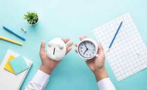 Hands holding a piggy bank and a clock, the cost-and-time trade-off behind the question can I do my own flood risk assessment.