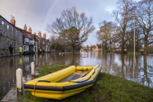 Flooded village street in England with a rescue dinghy, the river flooding that flood zones explained in this guide are meant to identify.