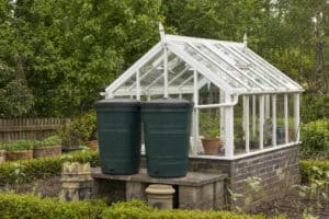 Water butts collecting greenhouse roof runoff, a small-scale SuDS feature of the kind the Surface Water Investment Model appraises.