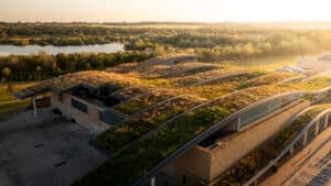 Undulating green roof beside a lake at sunset, illustrating the four pillars of SuDS in modern green infrastructure.