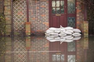 Sandbags stacked against a front door in floodwater, the residual risk a long term flood risk map describes.