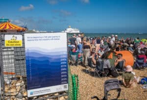 Sea level rise flood risk sign on Eastbourne beach showing predicted coastal sea level rise by decade to the 2120s.