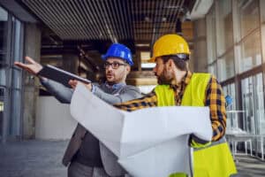 Two construction professionals disagreeing over site plans, showing the gap between building control and planning.