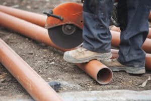 Contractor cutting drainage pipework on a construction site, work that can only begin after discharge of planning conditions.