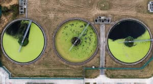 Aerial view of algae-covered wastewater treatment tanks, the kind of nutrient pollution behind nutrient neutrality rules in planning.