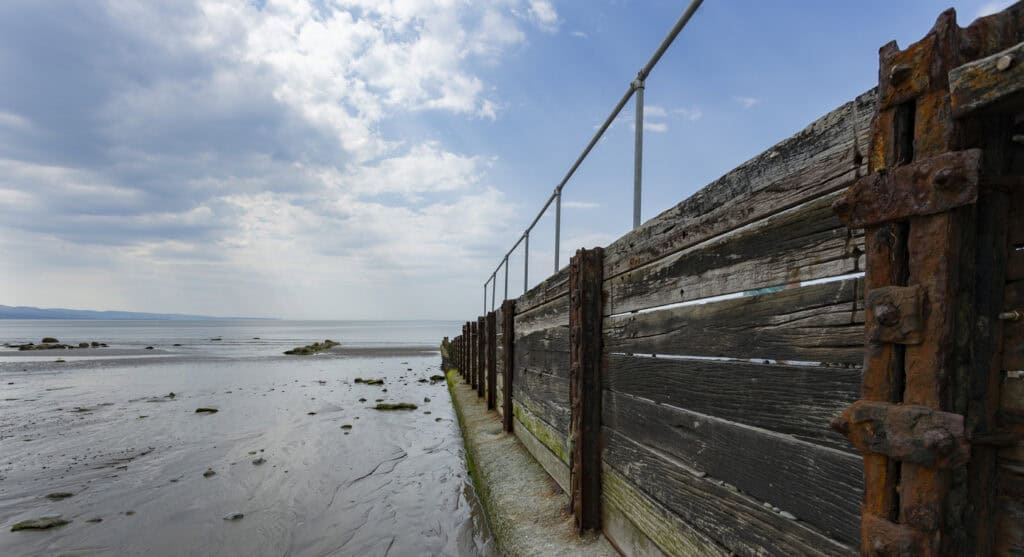An ageing timber and iron sea defence on a tidal shoreline, the kind of structure a shoreline management plan decides whether to maintain.