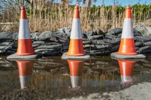 Traffic cones in floodwater behind sandbags, illustrating a CON29DW report guide to drainage and water searches.