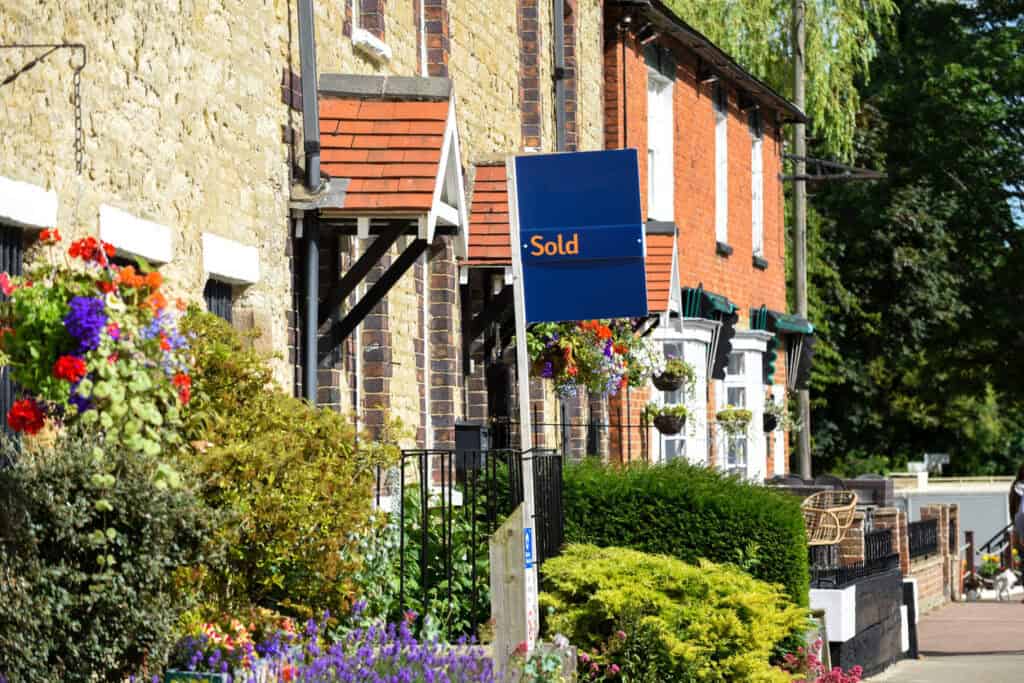 A "Sold" board outside a row of period terraced houses, where a conveyancing flood search would flag any flood risk before completion.