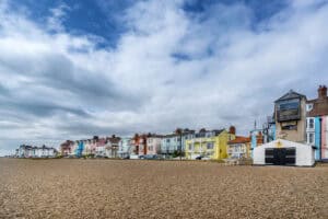 Colourful seafront houses behind a wide shingle beach, the kind of coastal setting a holiday let flood risk assessment must address.
