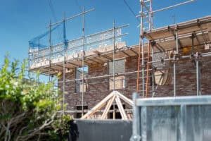 Brick house extension in a flood zone under construction, with scaffolding and new timber roof trusses being fitted.