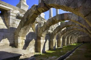 Rows of Roman stone arches beside a stone-lined channel, evoking the Roman drainage system and water engineering.