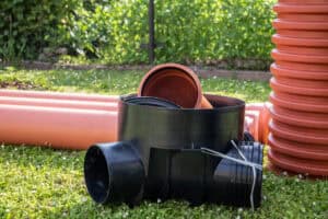 Underground drainage pipes and an inspection chamber base of the kind BS EN 752 covers, laid out on site before installation.
