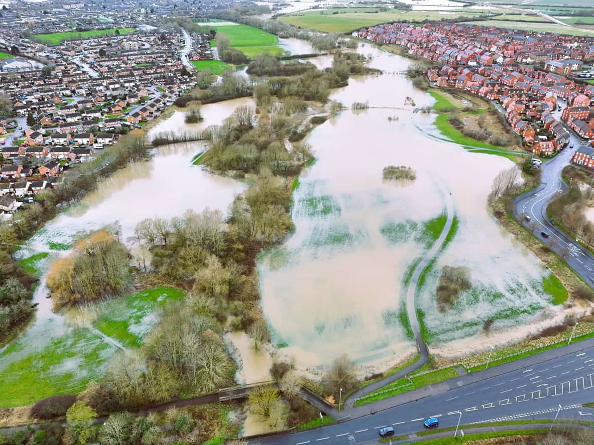 Flooded river corridor storing water between two housing estates, which is the function Flood Zone 3b exists to protect.