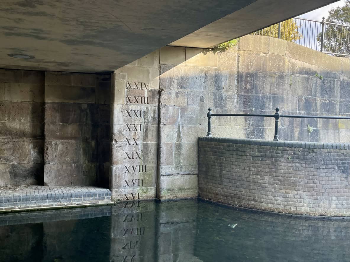 Roman numeral depth markers on a stone lock wall, recording water depth from a local point, not a level above Ordnance Datum.