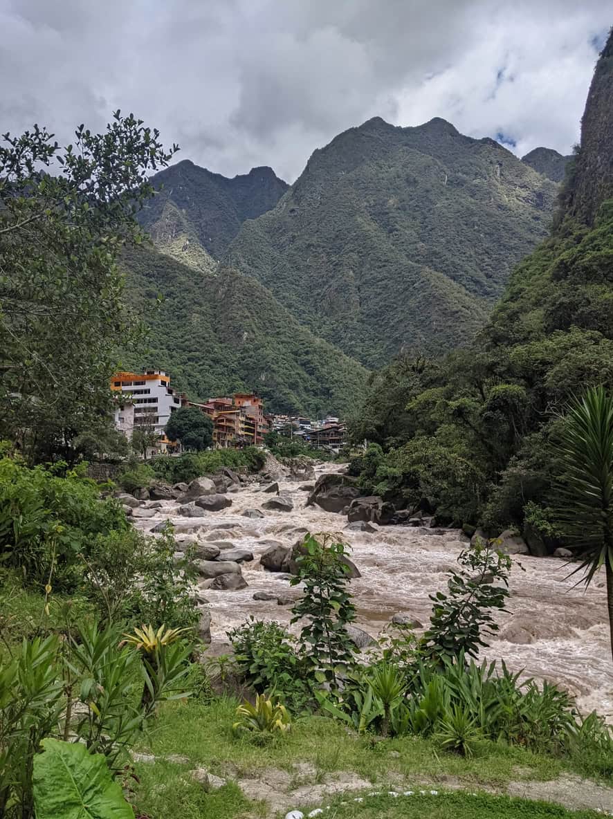 A river in spate through a steep forested gorge below the ridge, running brown with sediment after rain.