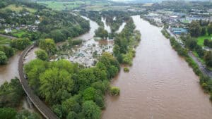 River in flood across its floodplain, covering allotments beside a railway, the kind of event that can lead to managed retreat.