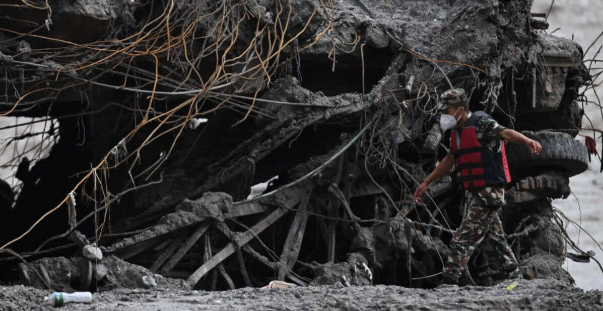 Rescue worker on mud-caked rubble and twisted reinforcement, from the Nepal disaster explained in this glacial lake outburst flood guide.