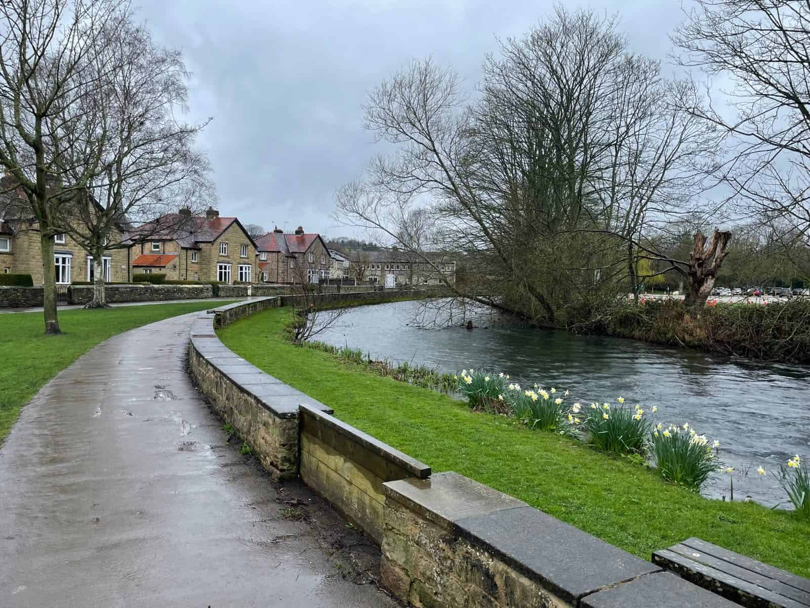Raised embankment and stone wall shielding riverside homes from a river in spate, one way people try to raise land out of the floodplain.