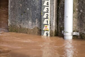 Gauge board in muddy, fast-flowing river water, a stage reading that needs converting before it can be compared with a level above Ordnance Datum.