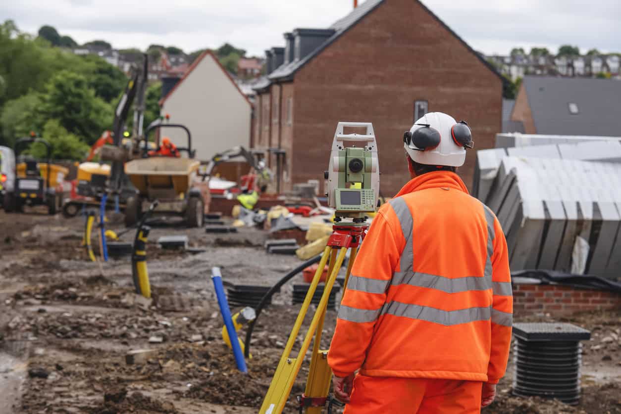 Surveyor using a total station on a housing site to record ground and floor levels above Ordnance Datum.