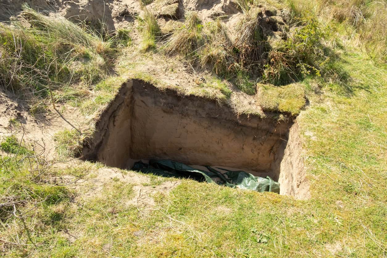 Excavated trial pit with vertical faces exposing sandy soils during a ground investigation on a development site.