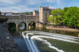 What is a weir: the River Avon spilling over the stepped, curved crests of Pulteney Weir below Pulteney Bridge in Bath.
