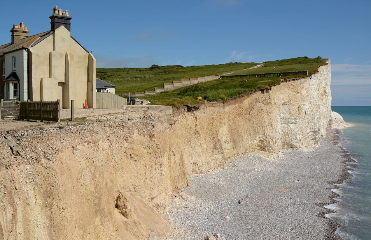 Cottage close to the edge of the eroding chalk cliff at Birling Gap, East Sussex, where coastal erosion is nearing homes.
