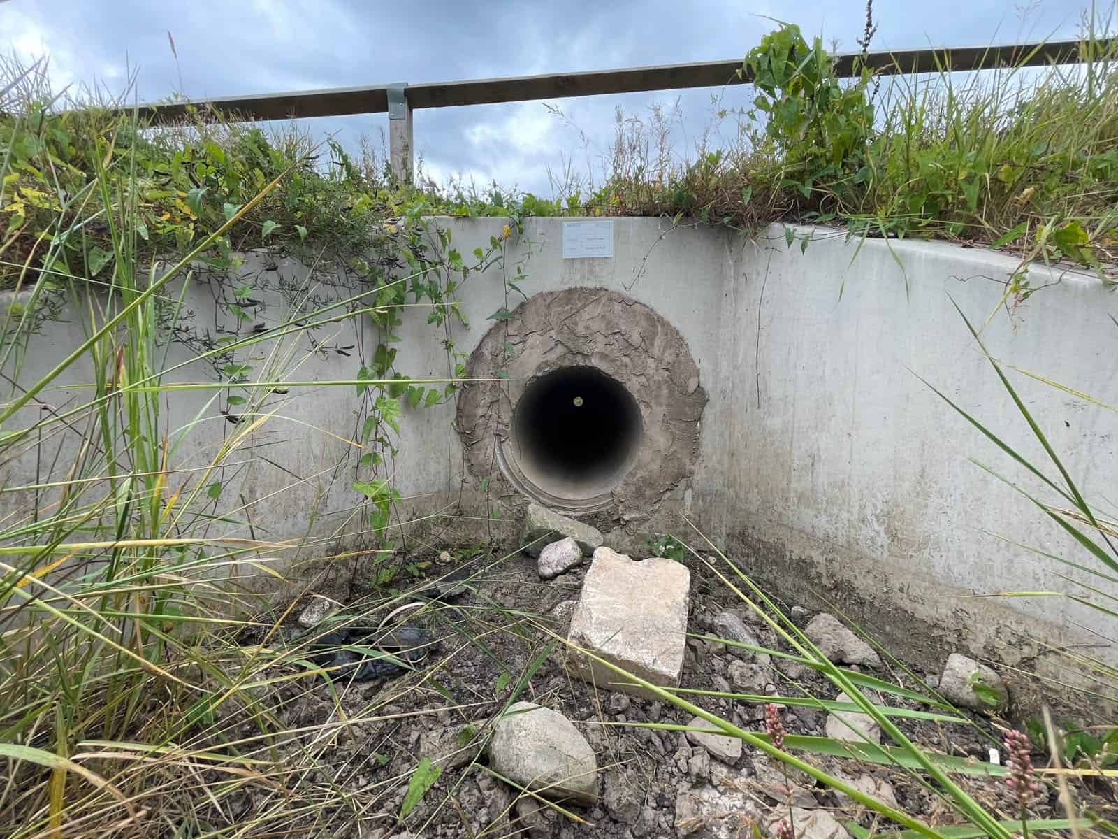 Concrete headwall and wingwalls around a pipe culvert on a dry channel bed, a typical answer to what is a culvert.