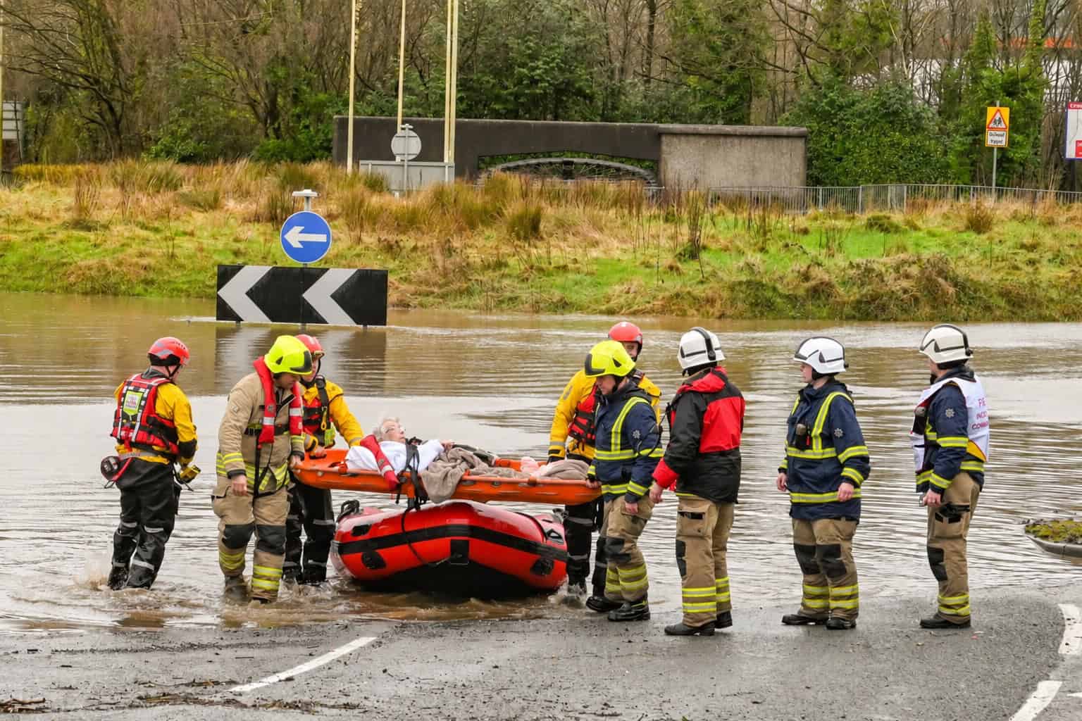 Fire and rescue crews carry a resident from a rescue boat across a flooded road, the kind of event Flood Action Week prepares for.