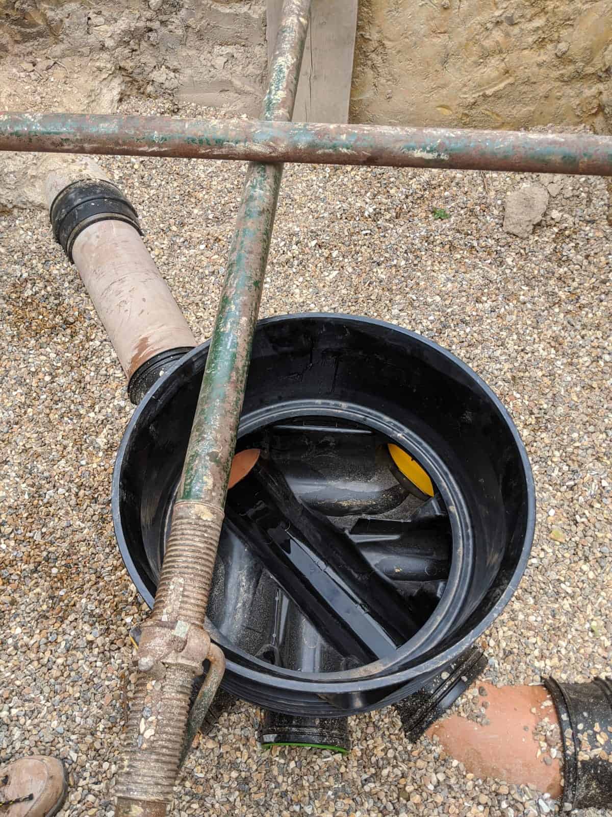 Plastic inspection chamber base with several inlets linking clay sewer pipes, sewer work of the kind a build over agreement can require.