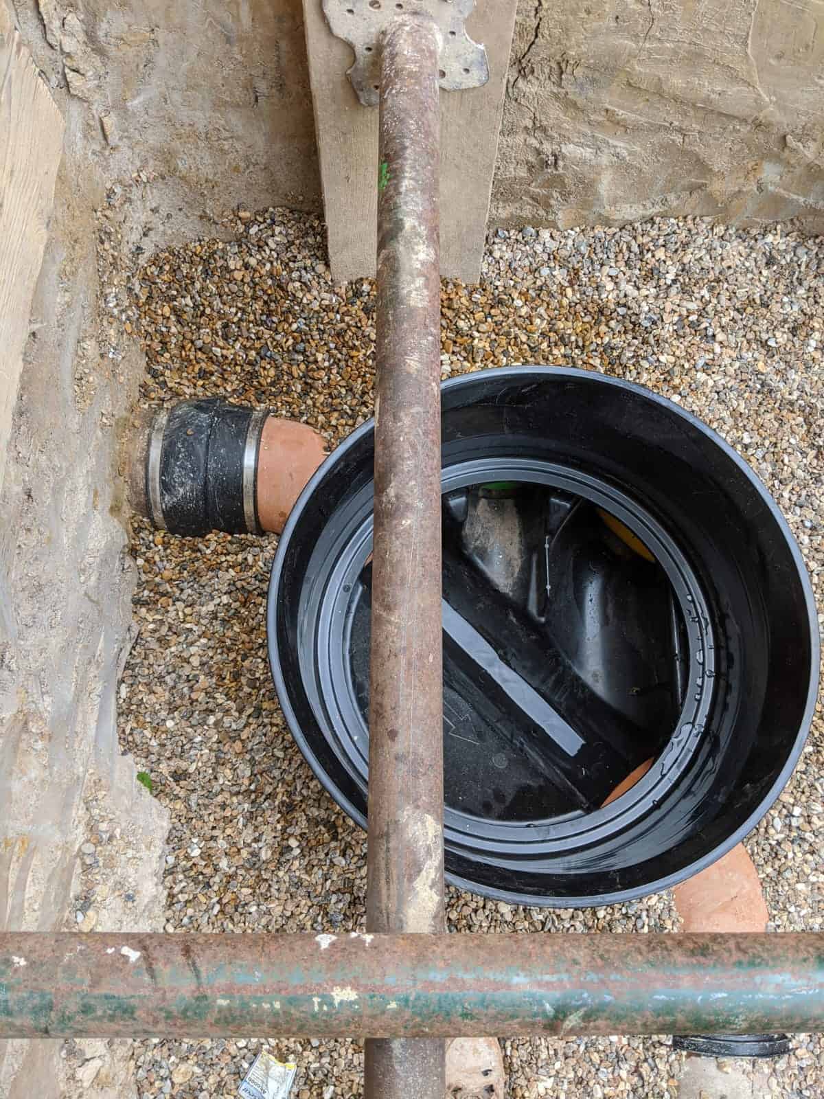 New plastic inspection chamber on pea gravel with a clay sewer pipe joining it, part of works where a build over agreement applies.