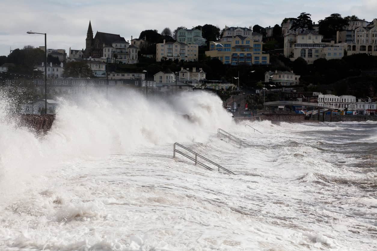 Waves overtopping the sea wall on Torquay seafront in a storm at high tide, the conditions a storm surge makes worse.